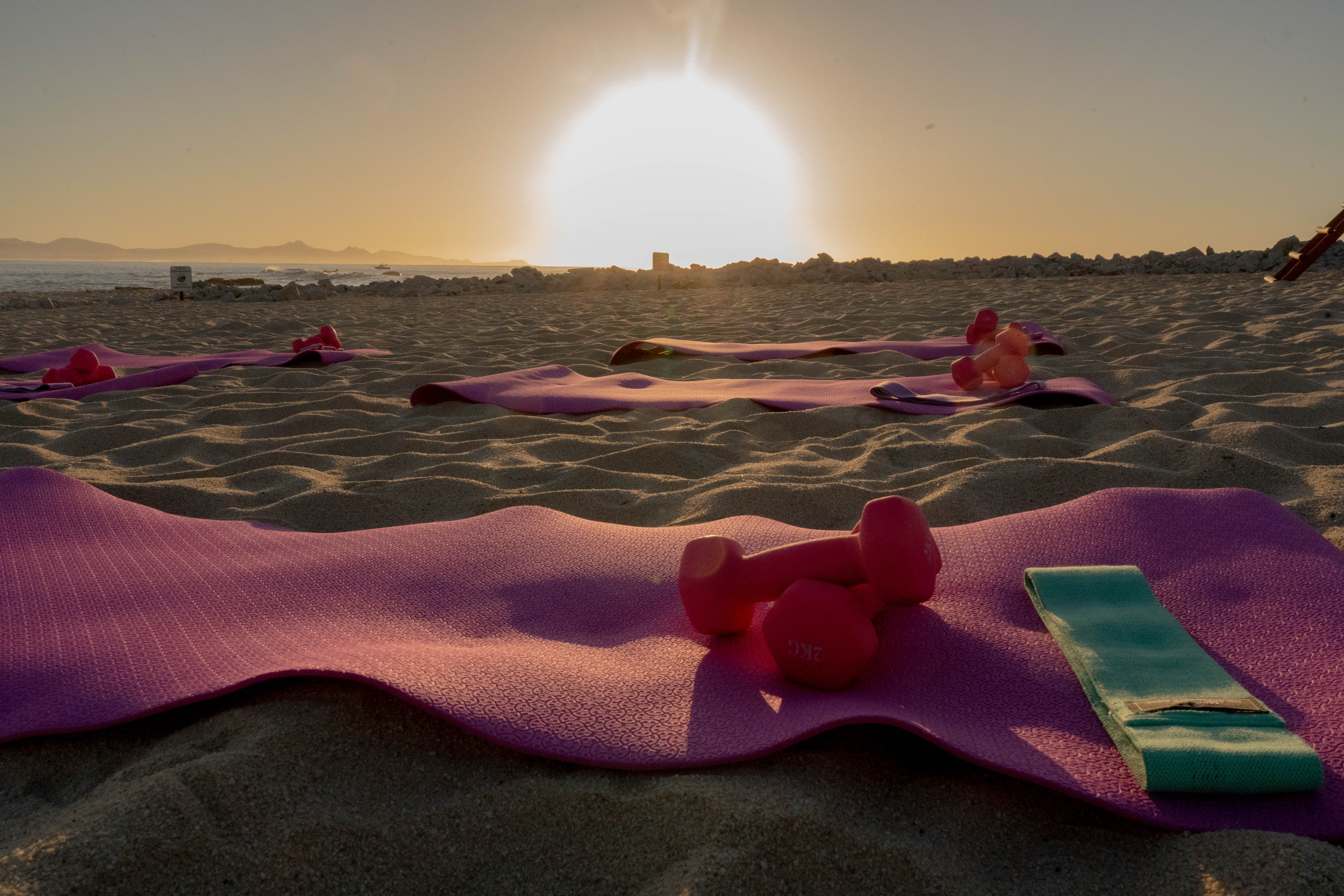 Tapetes y mancuernas en la playa al amanecer