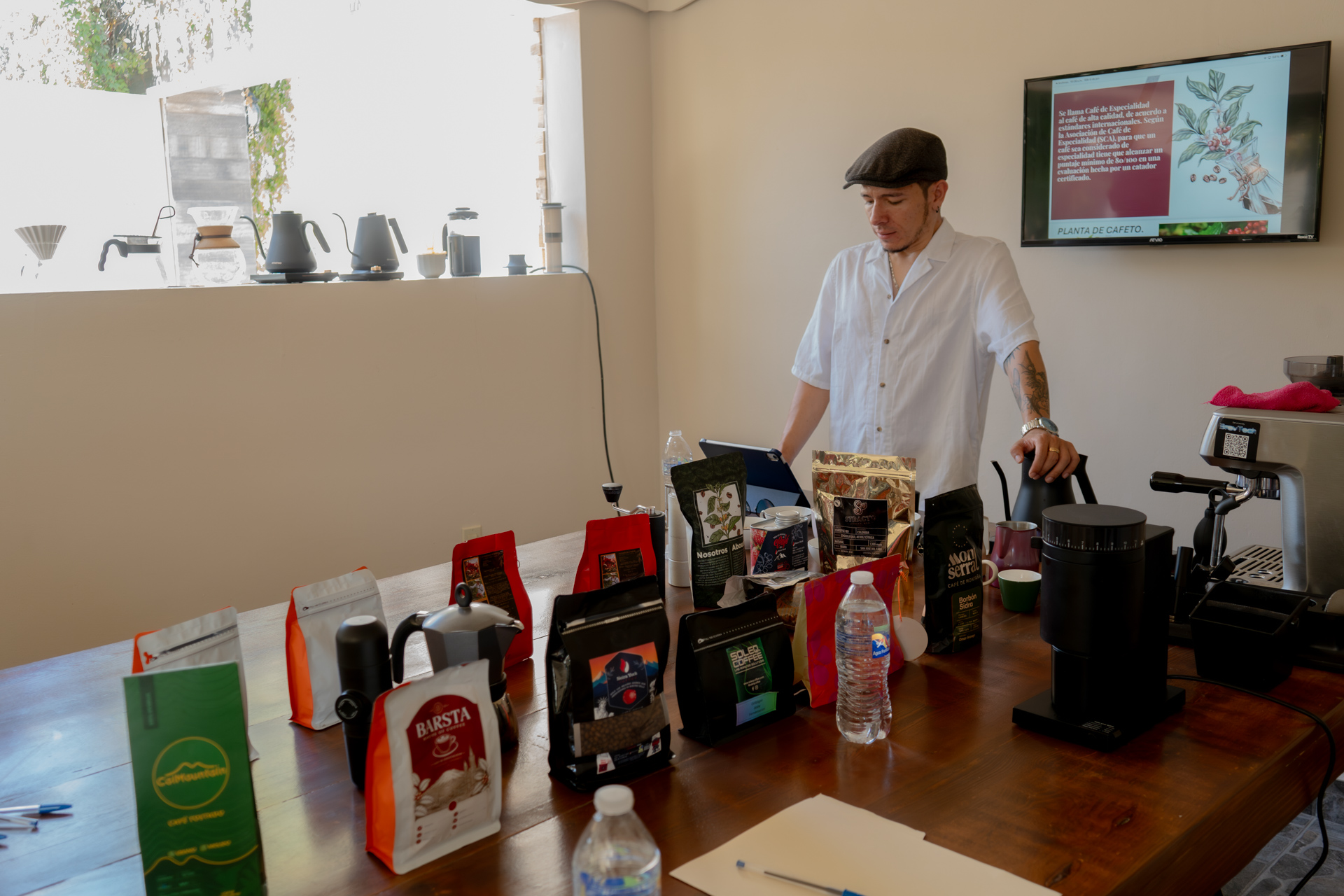 Instructor de pie con bolsas de café y pantalla didáctica