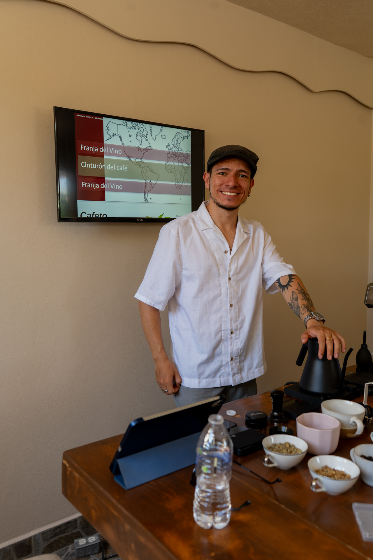 Instructor sonriendo ante el mapa y los granos sobre la mesa