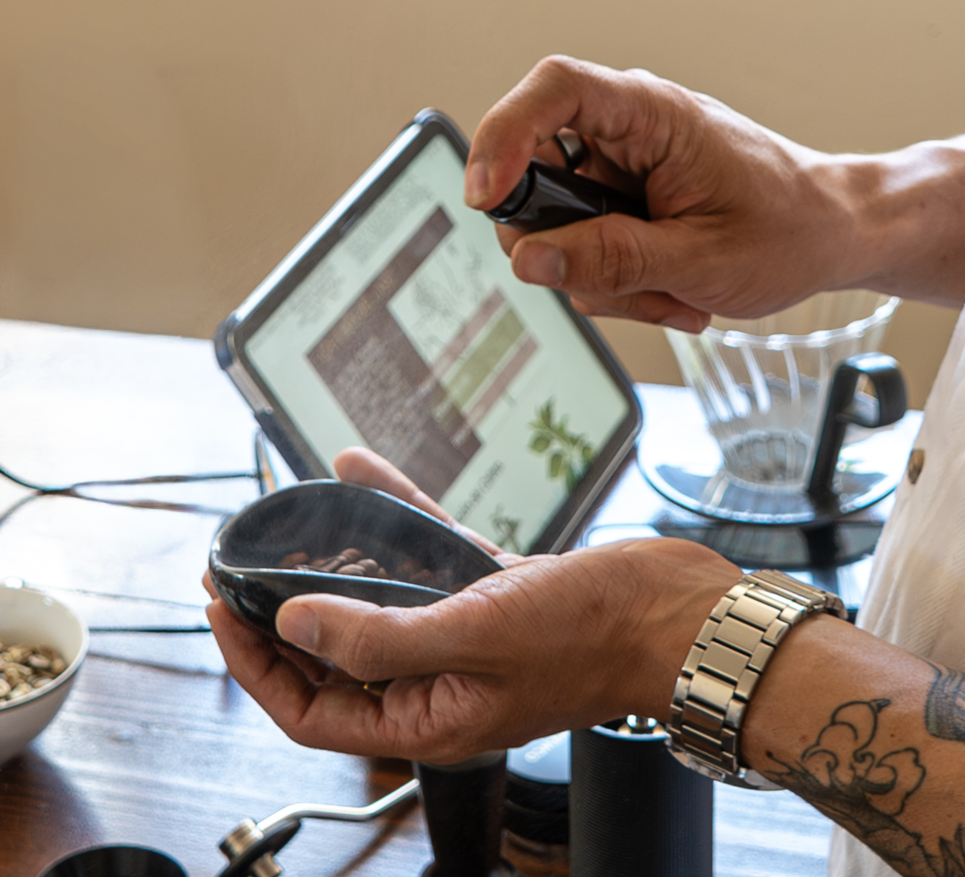 Manos tatuadas sosteniendo granos con tablet al fondo