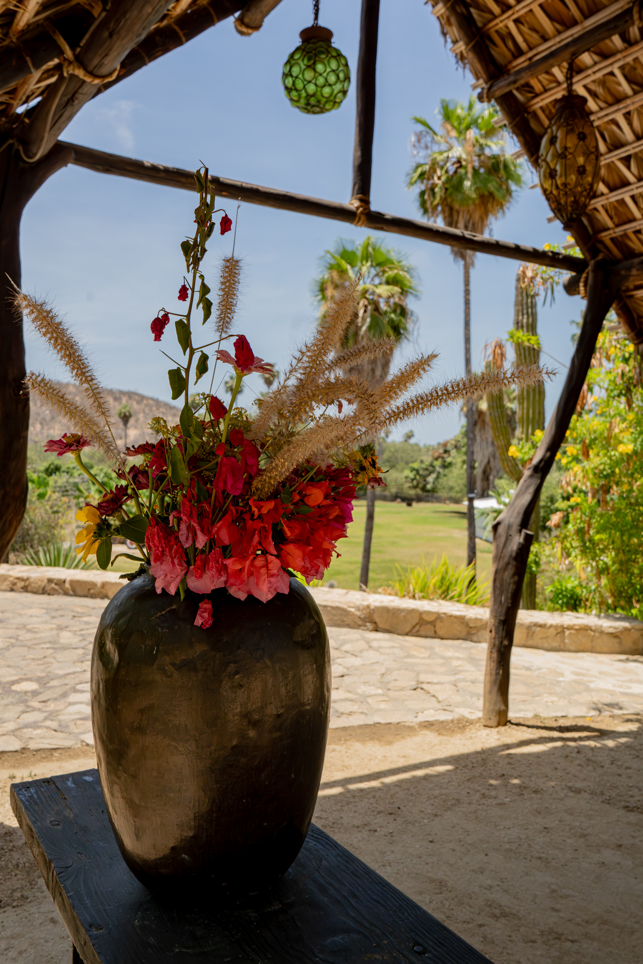 Jarrón de barro con flores rojas en el interior de la palapa
